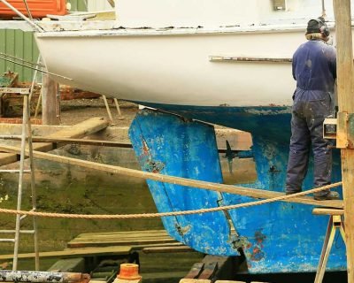 Mantenimiento-preventivo-embarcaciones-Barcelona Hombre reparando el casco de un velero